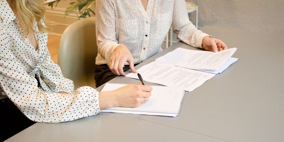 tow girls sitting signing an agreement